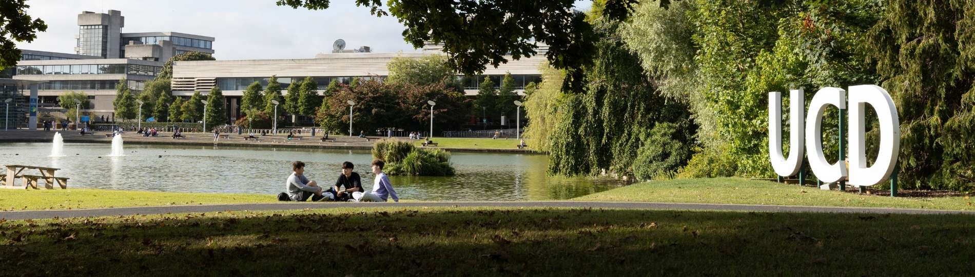 UCD Virtual Masters Week Homepage banner showing an image of three students sitting in front of the main UCD lake